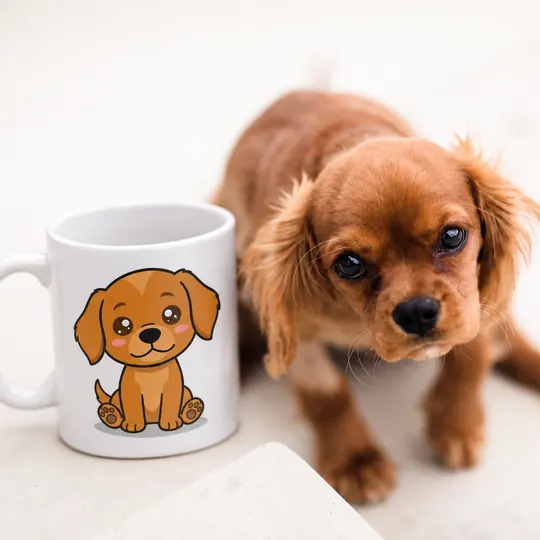 Un chiot cavalier king charles assis à côté d’un mug qui porte son portrait